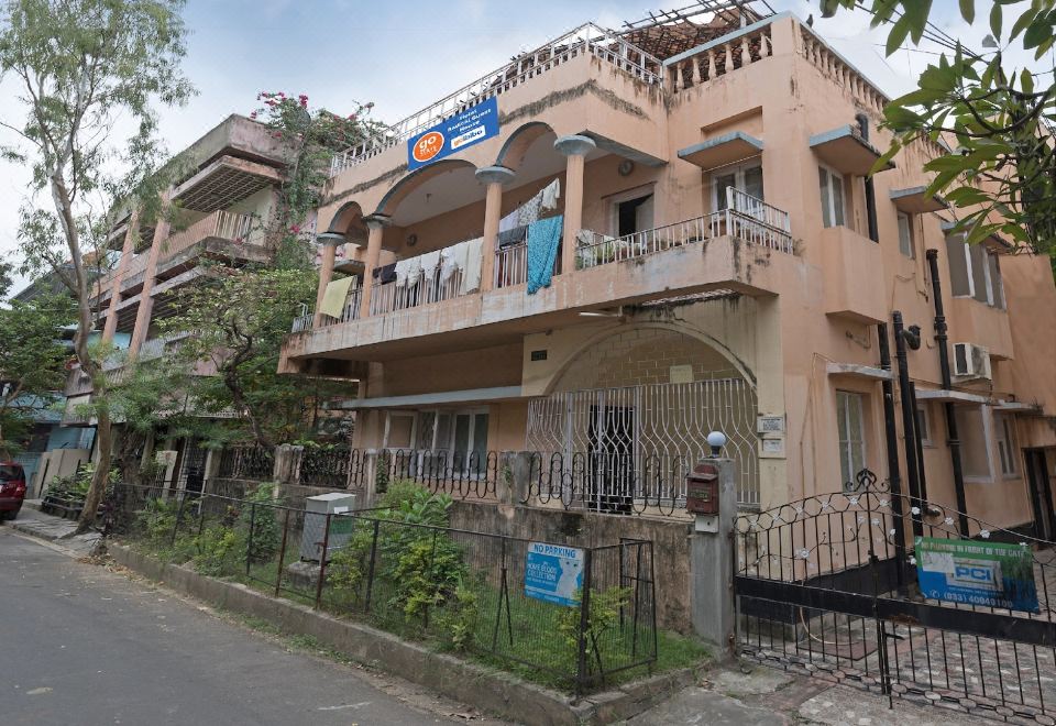 a three - story building with balconies and a blue sign on the front , located in a residential neighborhood at Radical