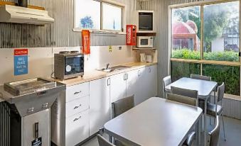 a kitchen with white cabinets , a stove , and a sink is shown with tables and chairs at Discovery Parks - Hadspen