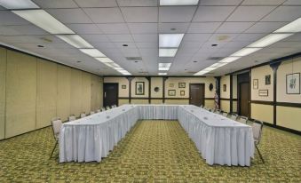 a large conference room with long tables covered in white tablecloths and chairs arranged in rows at Hotel Veranda DuBois