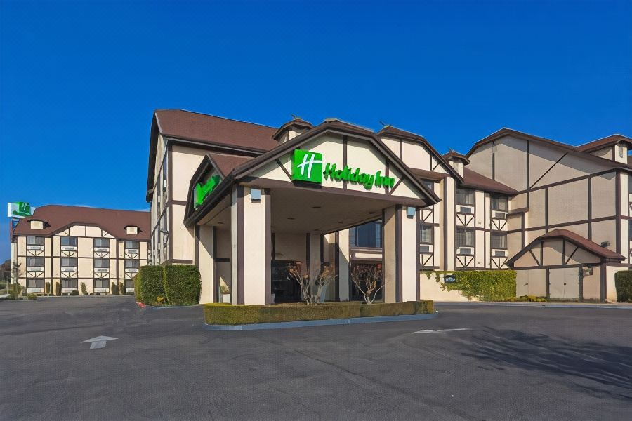 "a large building with a green sign that says "" holiday inn "" in front of it" at Holiday Inn Selma-Swancourt