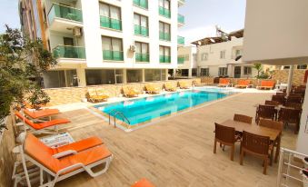 a large swimming pool with orange lounge chairs and tables is surrounded by a building at Altinersan Hotel