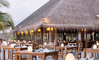 an outdoor dining area at a resort , with tables and chairs arranged for guests to enjoy a meal at Meeru Maldives Resort Island