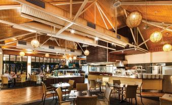 a modern , open - air restaurant with wooden floors and high ceilings , featuring multiple dining tables , chairs , and multiple windows at Travelodge Resort Darwin