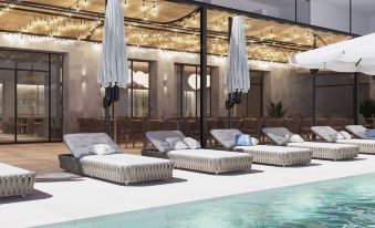 a row of lounge chairs and umbrellas are set up next to a swimming pool at Hotel Las Arenas