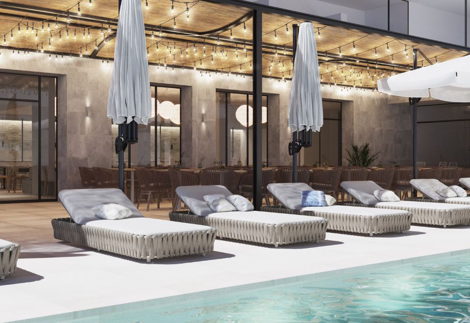 a modern swimming pool area with white lounge chairs and umbrellas , surrounded by a stone wall at Hotel Las Arenas