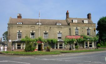 a large brick building with a red awning and ivy climbing up the side of the building at The Stratton House Hotel