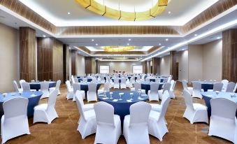 a large , empty banquet hall with white chairs and blue tables set up for a formal event at Favehotel Cimanuk Garut