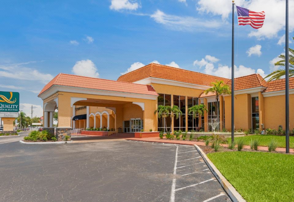 a large orange building with a flag flying in front of it , surrounded by trees and grass at Quality Inn & Suites Conference Center