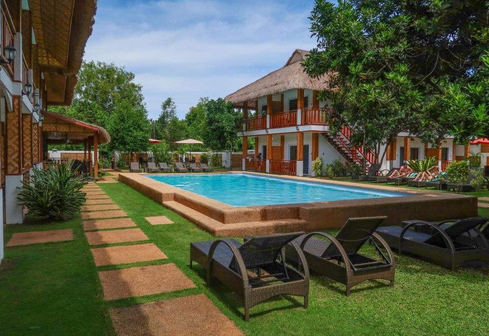 a large outdoor pool surrounded by lush greenery , with several lounge chairs placed around the pool area at Scent of Green Papaya