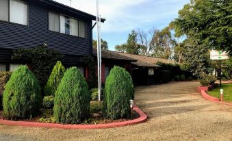 a large house with a driveway and bushes in front of it , surrounded by trees at Cottonwood Lodge