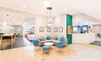 a modern living room with a couch , chairs , and dining table in the background at Holiday Inn Gloucester - Cheltenham