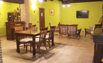 a dining room with wooden furniture , including a dining table and chairs , and a television mounted on the wall at La Contrada