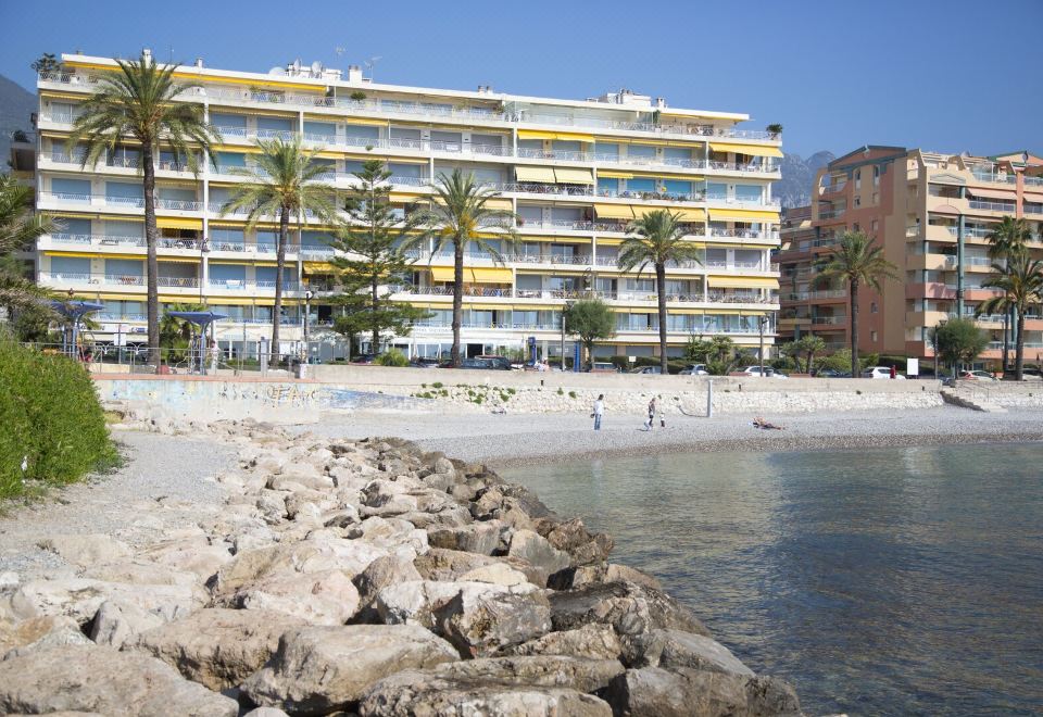 a beach scene with a group of people enjoying their time at the beach , surrounded by palm trees at Hotel Victoria