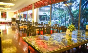 The restaurant features a spacious dining room with large windows and wooden tables that can accommodate up to 10 people at Ambassador Hotel Bangkok