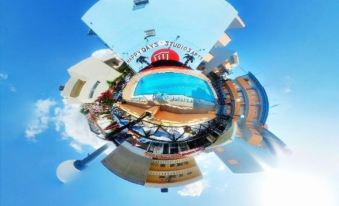 a small , circular , 3 6 0 - degree photo of a hotel pool area with palm trees and blue skies at Happy Days