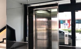 a large elevator with a clear door and windows is in an empty room with stairs at Arena Boutique Hotel Kuala Terengganu