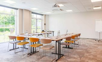 a conference room with tables and chairs arranged in rows , ready for a meeting or presentation at Mercure HAN Sur Lesse