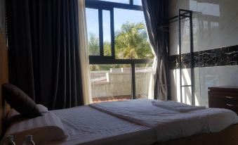 a bed with white sheets is in a room with a window and a railing at The Sea Rock Binh Hung