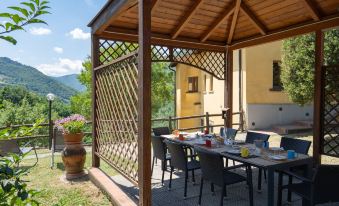 a wooden gazebo with a dining table set for a meal , surrounded by a lush green garden at Villa