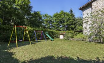 a backyard with a swing set , a slide , and a bench , surrounded by green grass and trees at Girasole