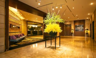 a hotel lobby with a large vase filled with yellow flowers , creating a welcoming atmosphere at Kawasaki Nikko Hotel