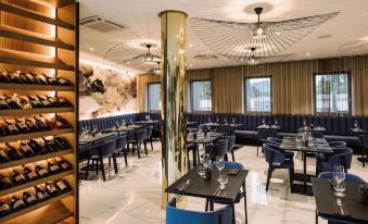 a modern restaurant with black tables , blue chairs , and gold column , under a gold ceiling light at Hotel A