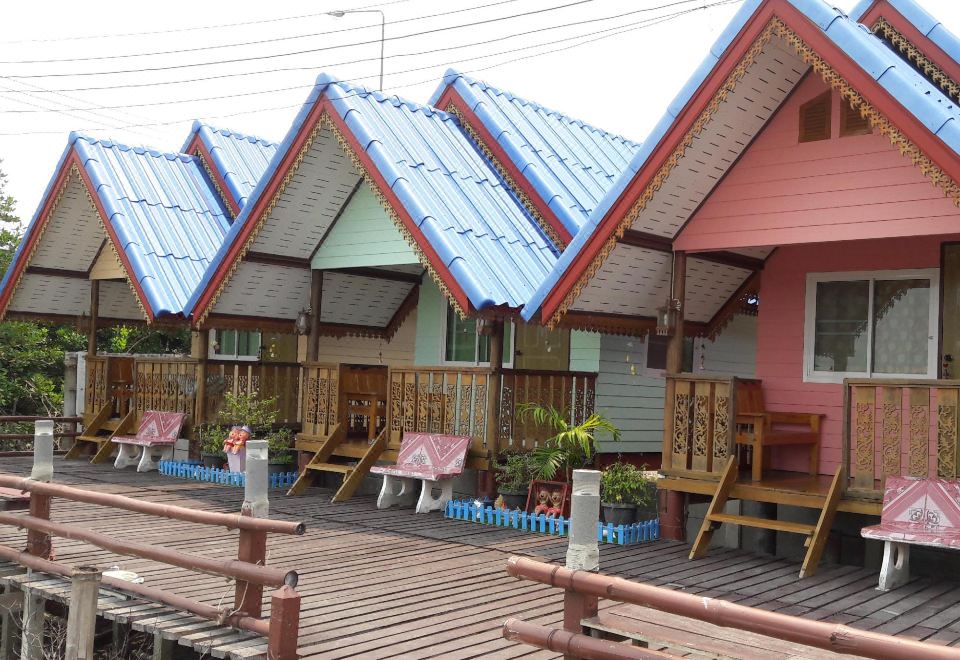 a group of colorful houses with blue roofs and wooden decks , surrounded by trees and a white fence at Sampaongern Home Stay