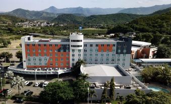 a large hotel surrounded by trees and mountains , with a view of the mountains in the background at Costa Bahia Hotel, Convention Center and Casino