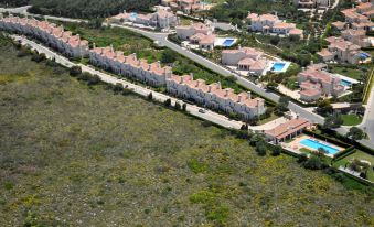 a residential area with multiple houses , trees , and a swimming pool surrounded by green grass at Martinhal Sagres Beach Family Resort Hotel
