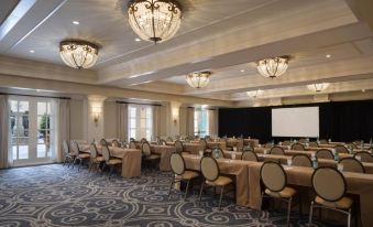 a large conference room with rows of tables and chairs , a projector screen , and chandeliers hanging from the ceiling at Lafayette Park Hotel & Spa