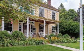 a large house with a porch and white columns is surrounded by green grass and trees at Van Winkle Inn