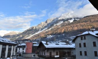 a snow - covered mountain village with houses and buildings , set against a blue sky filled with clouds at San Anton