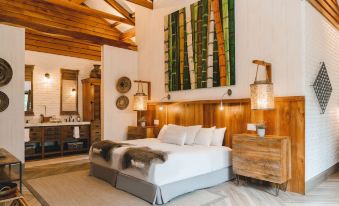 a large bed with white linens and a wooden headboard is in a room with a painting on the wall at Hacienda la Danesa