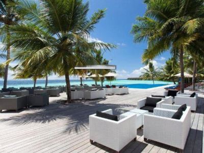 a resort with a pool surrounded by lounge chairs and palm trees , providing a relaxing atmosphere at Vilamendhoo Island Resort & Spa