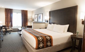 a large bed with a white and brown blanket is in the middle of a room at Oxford Suites Pendleton