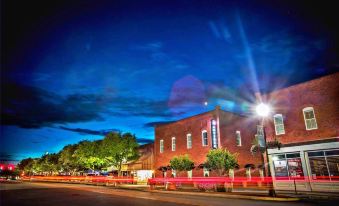 a nighttime view of a building with red lights and trees in the foreground , taken from the perspective of an unseen angle at The Mantissa Hotel