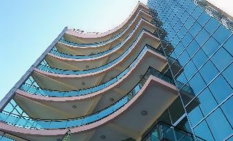 a modern building with a unique curved design is shown from a low angle against a clear blue sky at Delano Hotel Bahir Dar