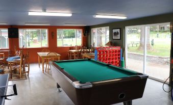 a billiards table in a room with multiple windows , surrounded by dining tables and chairs at Lone Fir Resort