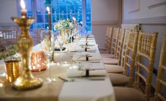 a long dining table set for a wedding reception , with multiple chairs arranged around it at The Blue Boar