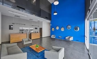 a modern office lobby with blue walls , wooden furniture , and a blue ceiling , along with a dining area and reception desk at City Express by Marriott Cdmx la Villa