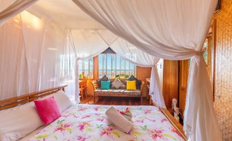 a bed with a floral blanket and colorful pillows is in a room with a large window at 1770 Beach Shacks
