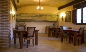 a room with wooden tables and chairs , a large painting on the wall , and chandeliers hanging from the ceiling at La Contrada