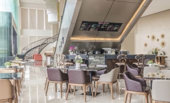 a modern hotel lobby with a large reception desk , multiple chairs , and a staircase leading to the upper level at Marcian Garden Hotel