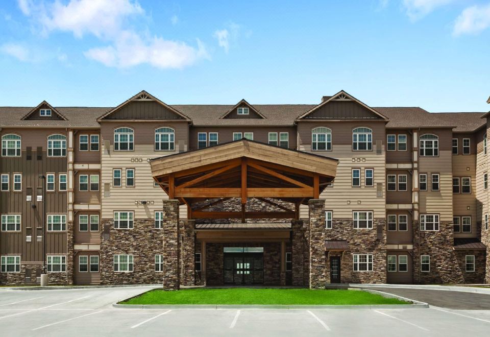 an apartment building with a wooden entrance and a parking lot in front of it at Hyatt House Minot