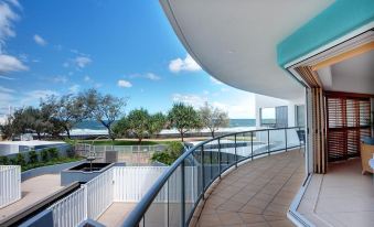 a balcony with a glass railing overlooking a body of water , providing a scenic view at Rolling Surf Resort Sunshine Coast