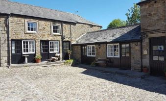 a stone house with a paved courtyard in front of it , surrounded by a fence at The Ancient Unicorn