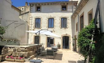 a courtyard with a table , chairs , and an umbrella is surrounded by a stone wall at La Bastide