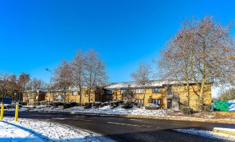 a sunny day with a clear blue sky and snow - covered trees , as well as a row of buildings with balconies at Days Inn by Wyndham London Stansted Airport