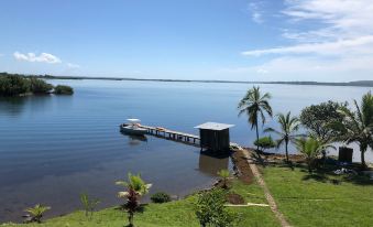 a serene lake scene with a dock , dock house , and palm trees in the background at Casa Piedra