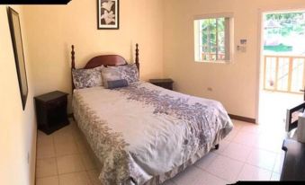 a bedroom with a large bed , wooden headboard , and a window with framed pictures on the wall at Paradise Reggae Resort